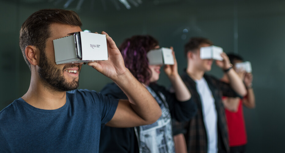 A line of students looking into VR equipment