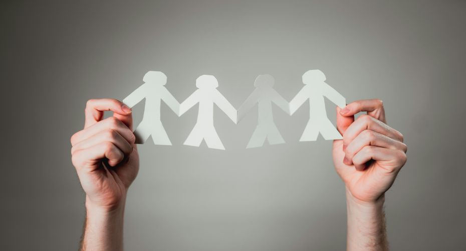 Two hands holding up a string of paper dolls