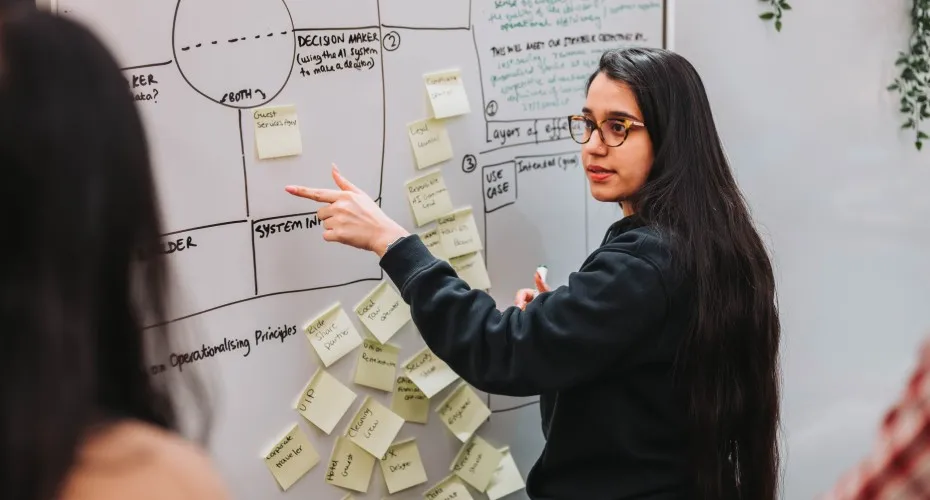 A student points to a whiteboard covered in sticky notes during an industry-led group training day.