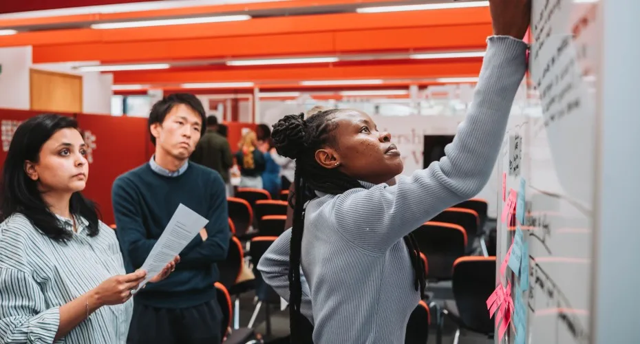 A group of students engaged in discussion around a whiteboard during an industry-led training day.