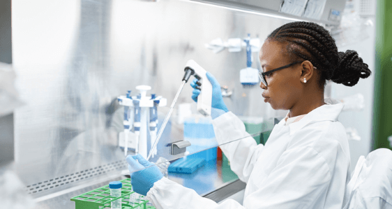 Female student wearing lab coat and gloves, using test tubes