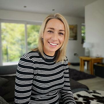 A woman wearing a striped top, smiles to camera