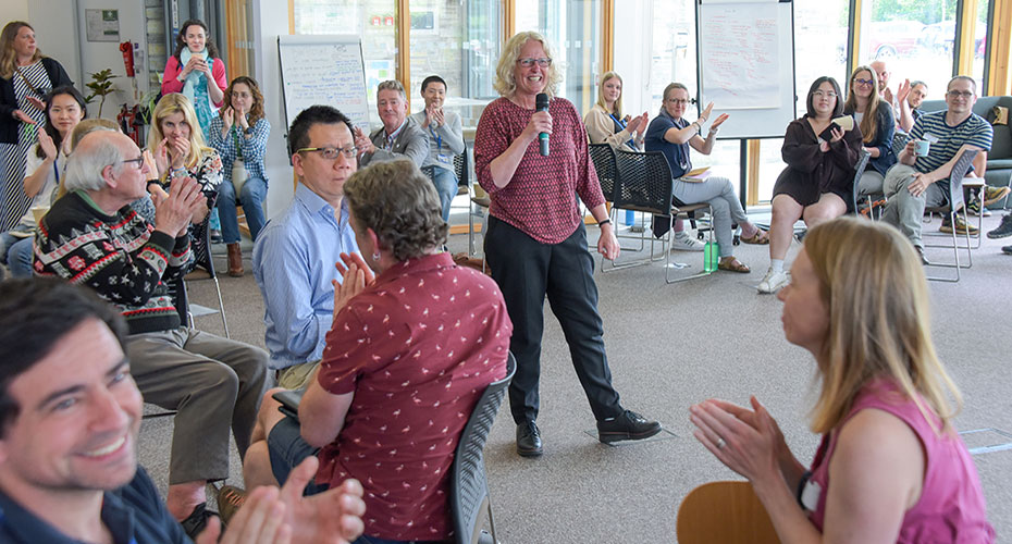 A diverse group of individuals sitting in chairs, applauding enthusiastically.