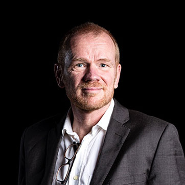 Professor Frank van Veen is photographed in stock studio lighting against the dark background.