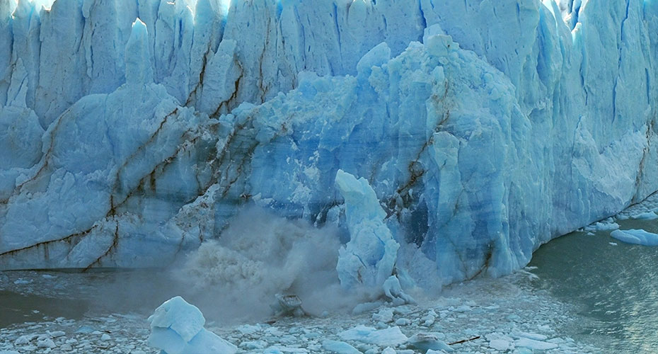 view of massive ice chunks of ice collapsing from a glacier into the water.