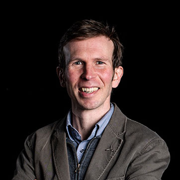 Professor Richard Cochrane portrait in studio light against a dark background.