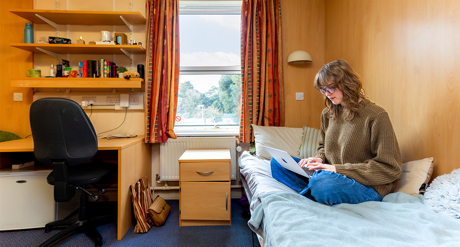 A student working on a laptop in a Ransom Pickard bedroom