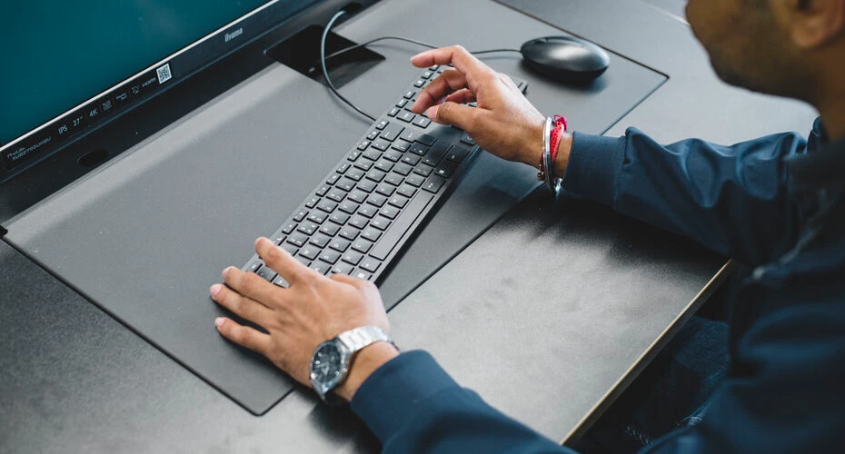 Image taken over a students shoulder, looking down whilst the student types on a laptop