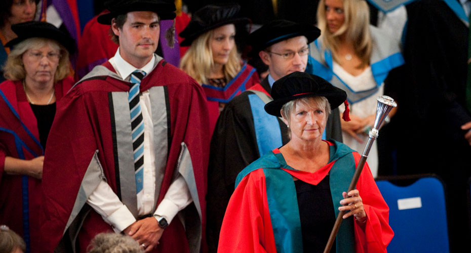 Female academic leading graduation procession in traditional robes
