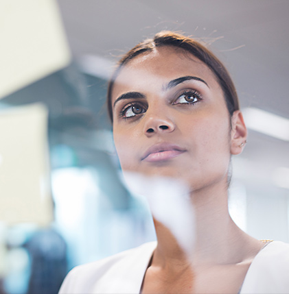 A woman standing and looking up at a window, deep in thought.