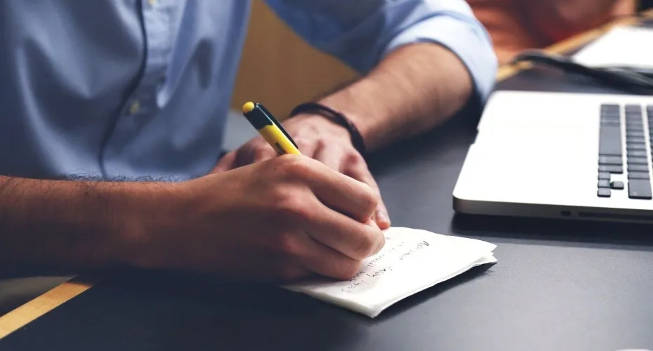 A person focused on writing with a pen on a piece of paper, capturing his thoughts in a notebook.